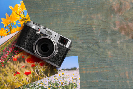 Vintage photo camera and beautiful printed pictures on wooden table, flat lay with space for text. creative hobbyの写真素材