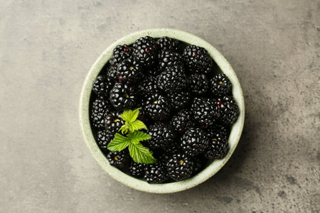 Bowl with fresh ripe blackberries on gray table, top view