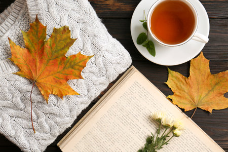 Flat lay composition with cup of aromatic tea and soft sweater on wooden table. autumn atmosphere