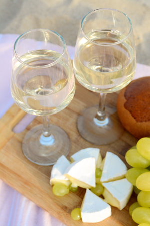 Glasses with white wine and snacks for beach picnic on sand outdoorsの写真素材