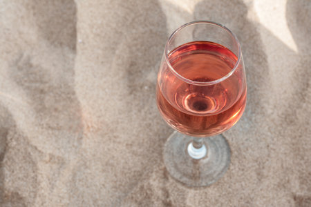 Glass of tasty rose wine on sand, above view. Space for textの写真素材