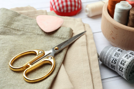 Scissors, spools of threads and sewing tools on white wooden table, closeupの写真素材