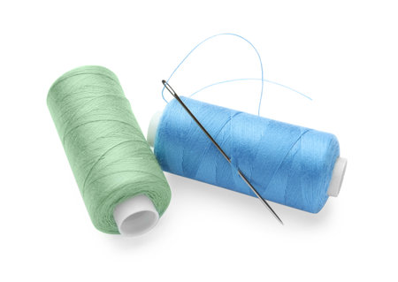 Different colorful sewing threads with needles on white background