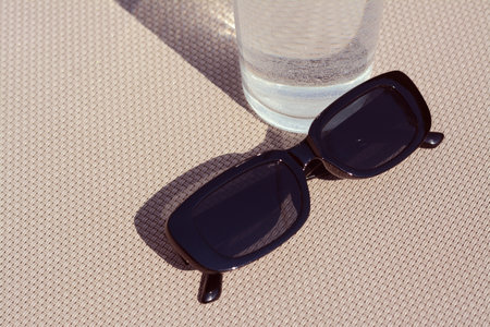 Stylish sunglasses and glass of water on gray surface, closeupの写真素材