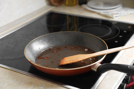 Frying pan with spatula and used cooking oil on stoveの写真素材
