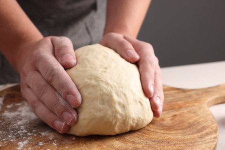 Man kneading dough at table near gray wall, closeup