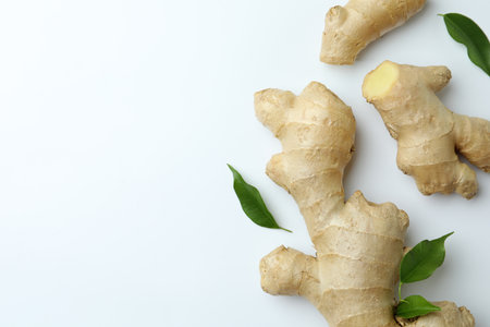 Fresh ginger with green leaves on white background, flat lay. Space for text