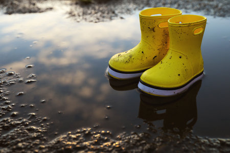 Yellow rubber boots in puddle outdoors, space for text. autumn walkの写真素材