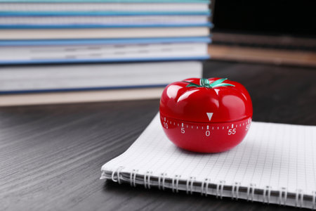 Kitchen timer in shape of tomato and notebook on wooden table, space for textの写真素材