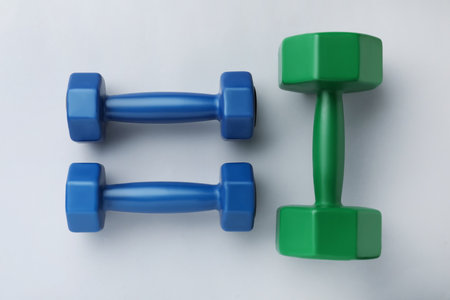 Colorful vinyl dumbbells on light background, flat lay