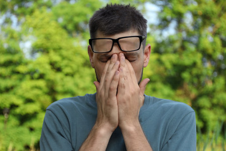 Man suffering from eyestrain outdoors on sunny dayの写真素材