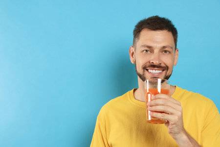 Man drinking delicious juice on light blue background, space for textの写真素材
