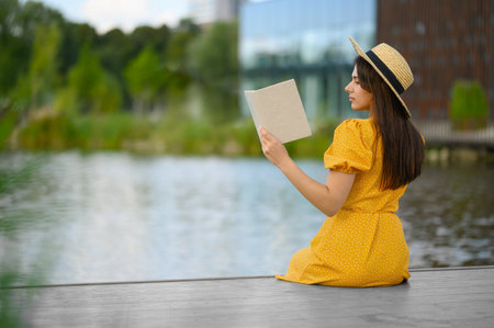 Young woman reading book on pier near lake
