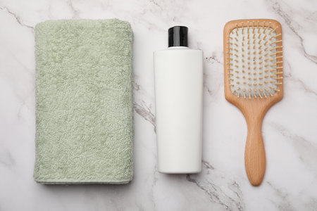Shampoo bottle, towel and hair brush on white marble table, flat layの写真素材