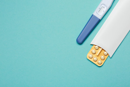 Birth control pills and pregnancy test on light blue background, top view. Space for textの写真素材