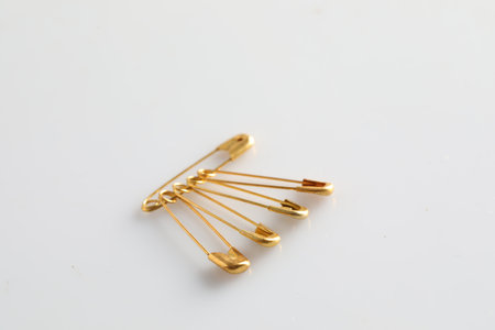 Golden safety pins on white background, space for text