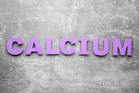 Word Calcium made of violet paper letters on gray background, top viewの写真素材