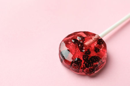 Sweet colorful lollipop with berries on pink background, closeup. Space for textの写真素材
