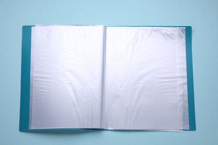 File folder with punched pockets and paper sheets on turquoise background, top viewの写真素材