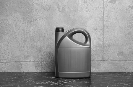 Motor oil in canister on black table near gray wallの写真素材