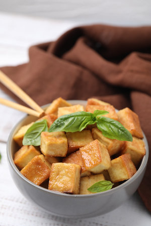 Bowl with delicious fried tofu and basil on white tableの写真素材