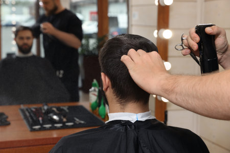 Professional hairdresser working with client in barbershop, closeupの写真素材