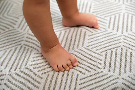 Cute baby learning to walk on carpet, closeup