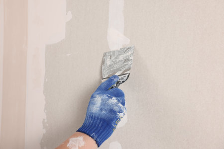 Man plastering wall with putty knife indoors, closeup. home renovationの写真素材