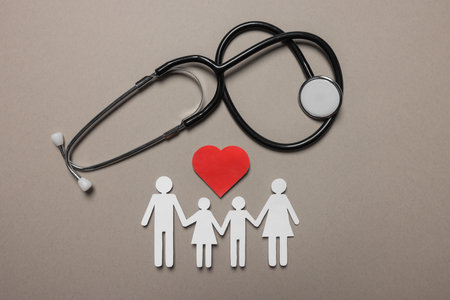 Paper family figures, red heart and stethoscope on light gray background, flat lay. insurance conceptの写真素材