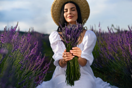 Beautiful young woman with bouquet in lavender fieldの写真素材