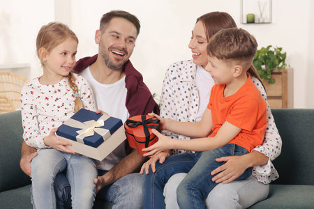 Happy family presenting each other with gifts on sofa at homeの写真素材