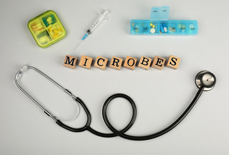 Word Microbes made with wooden cubes, pills and stethoscope on light background, flat layの写真素材