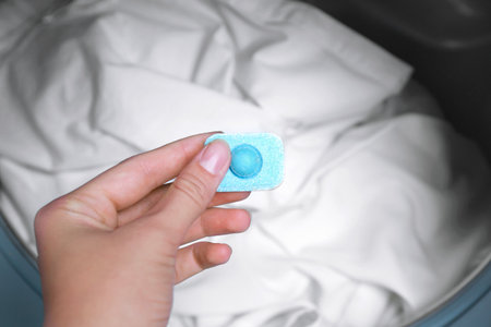 Woman putting water softener tablet into washing machine, closeup
