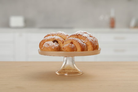 Stand with delicious croissants on wooden table in kitchen
