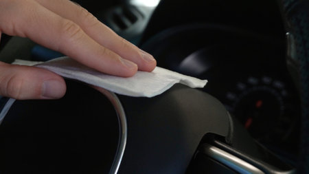Man cleaning steering wheel with wet wipe in car, closeup. protective measuresの写真素材