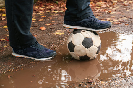 Man with soccer ball in muddy puddle outdoors, closeupの写真素材