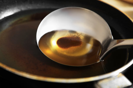 Frying pan and ladle with used cooking oil on stove, closeupの写真素材