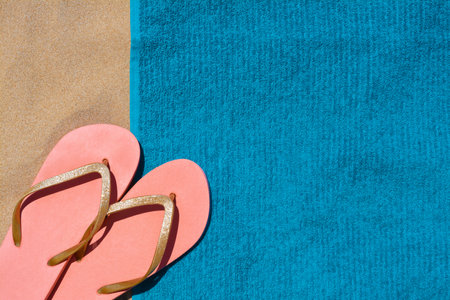 Soft blue beach towel with flip flops on sand, flat layの写真素材