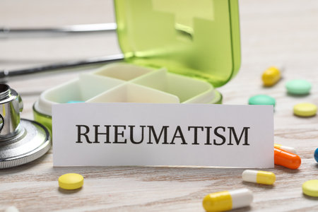 Card with word Rheumatism, stethoscope and pills on white wooden table, closeupの写真素材