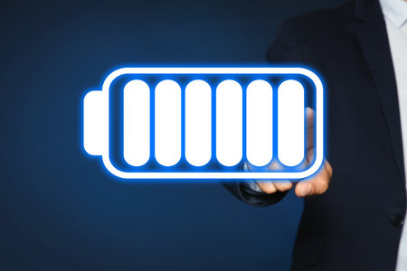 Businessman demonstrating at icon of full battery on color background, closeup