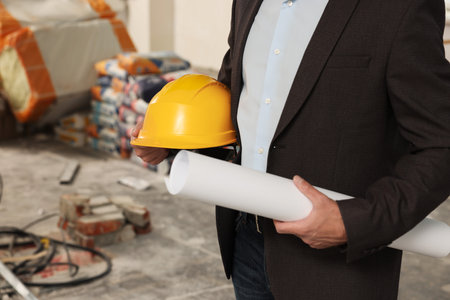 Professional engineer with hard hat and draft indoors, closeup