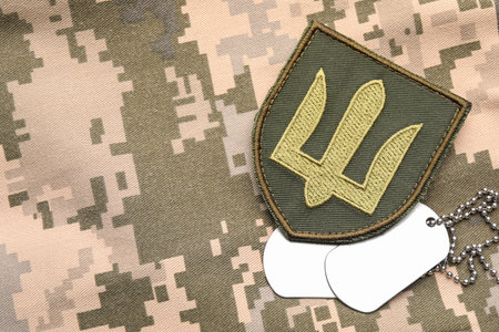 Military ID tags and patch on pixel Ukrainian camouflage, flat lay. Space for text