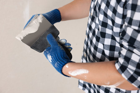 Worker with putty knives and plaster indoors, closeup. home renovationの写真素材
