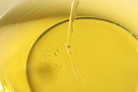 Pouring cooking oil into glass bowl, closeup