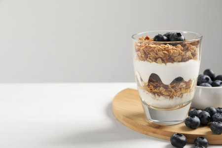 Yogurt served with granola and blueberries on white wooden table, space for textの写真素材