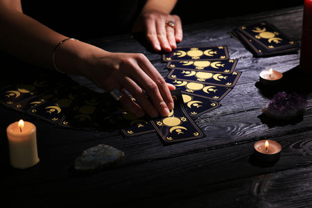 Soothsayer predicting the future with tarot cards at table in darkness, closeupの写真素材