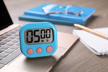 Kitchen timer and laptop on wooden table, closeup. Space for text