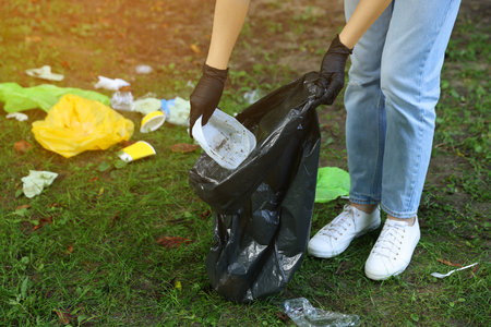 Woman with plastic bag collecting on green grass, closeupの写真素材