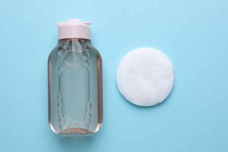 Micellar water and cotton pad on light blue background, flat layの写真素材