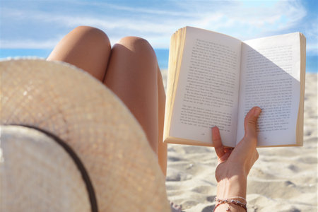 Woman reading book on sandy beach near sea, closeupの写真素材